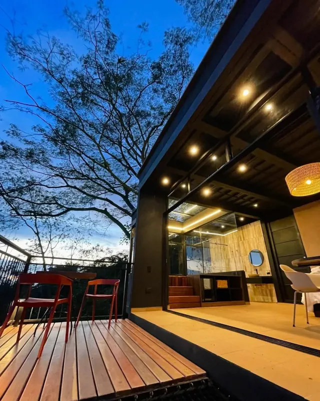 Terraza de hotel con iluminación cálida al atardecer, mobiliario exterior y ambiente tranquilo, ideal para hotel boutique y glamping.