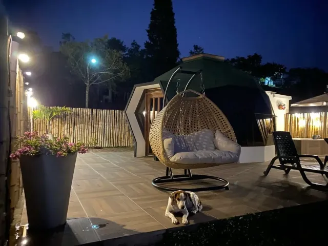Glamping Bucaramanga con domo iluminado y terraza exterior de noche en entorno natural.