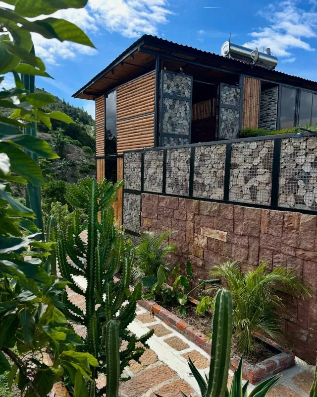 Cabaña ecológica de dos niveles con fachada en madera y bambú, diseño natural y sostenible ideal para glamping para parejas.