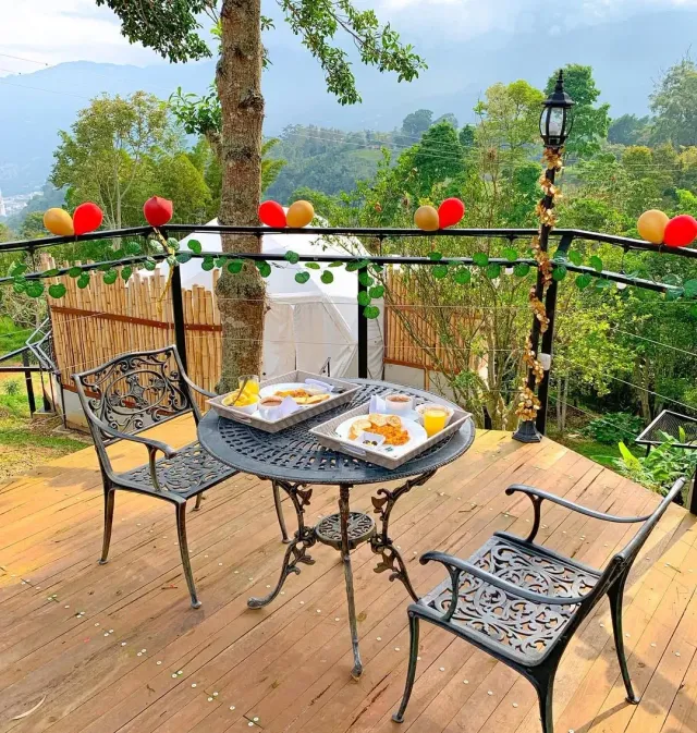 Desayuno servido en terraza de glamping con mesa al aire libre y vistas a la naturaleza, ideal para una experiencia glamping relajada.