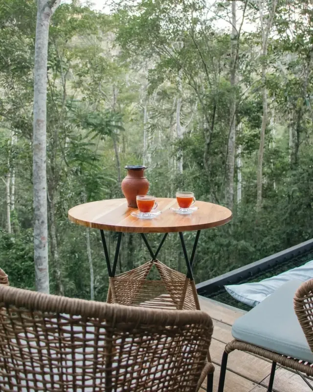 Terraza privada de glamping para parejas con mesa, copas de vino y vista natural rodeada de bosque, ambiente romántico y exclusivo.