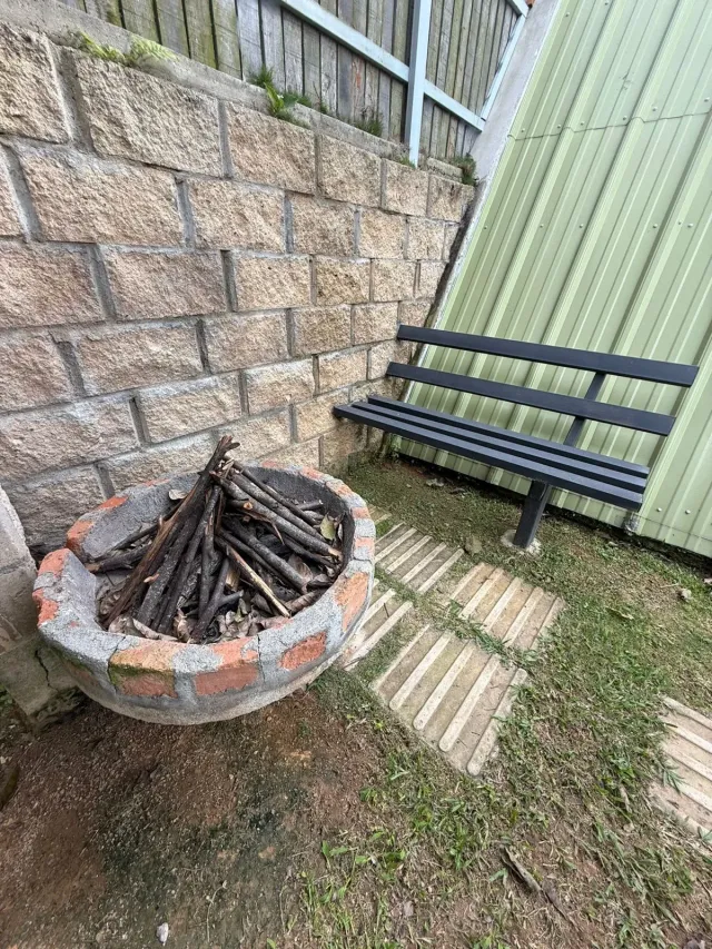 Zona exterior de glamping con fogata de leña y banca, ideal para descansar y compartir momentos en una experiencia glamping natural.