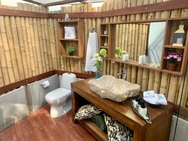 Baño ecológico con paredes de bambú y lavamanos en piedra en glamping Bucaramanga.