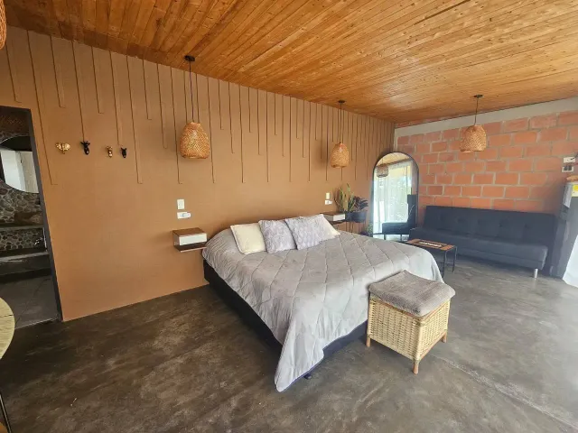Suite de glamping Bucaramanga con cama king, techo en madera y diseño moderno en ambiente cálido.