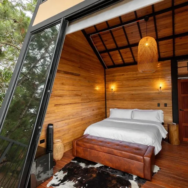 Habitación tipo cabaña con cama doble y decoración en madera en glamping Bucaramanga.