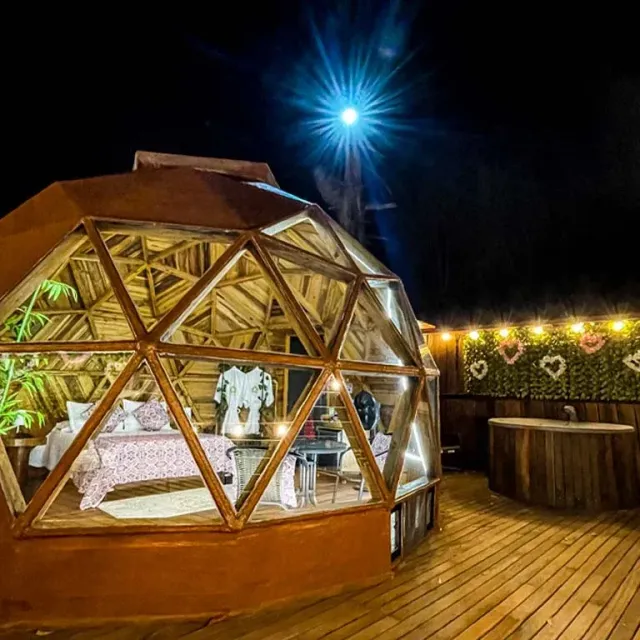 Domo geodésico iluminado con jacuzzi exterior en glamping Bucaramanga.