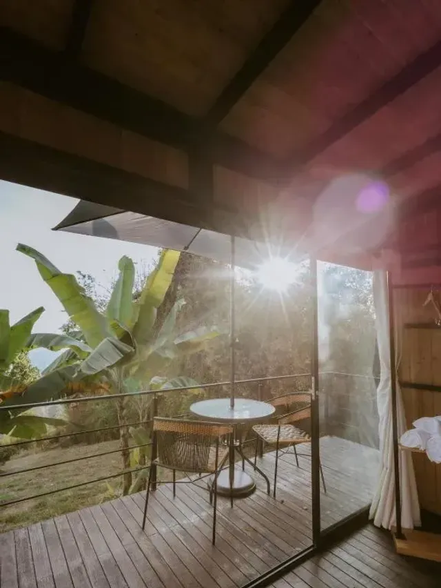 Balcón con mesa de mimbre y vista al amanecer en glamping Bucaramanga.