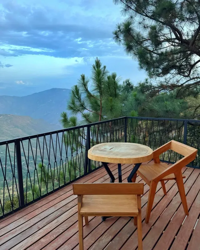 Terraza de glamping con mesa de madera y vista panorámica a las montañas de Bucaramanga.