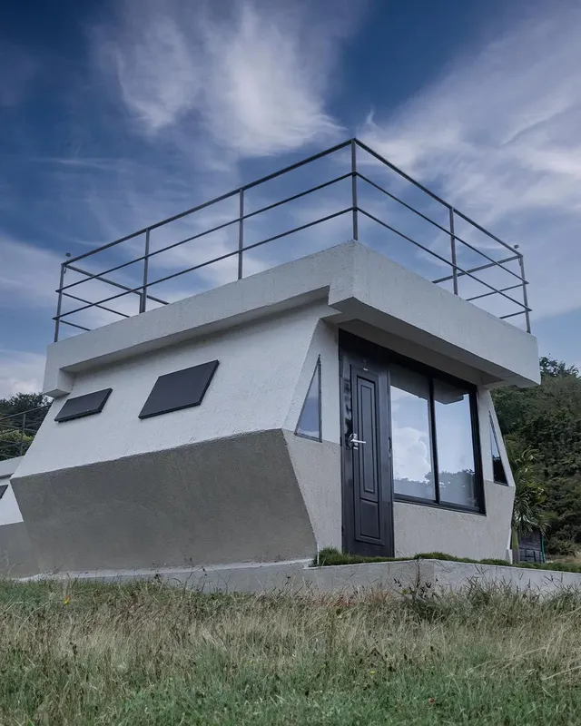 Cabaña de glamping de diseño geométrico con ventanales amplios, ideal como alojamiento moderno rodeado de naturaleza.