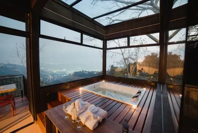 Jacuzzi interior con toallas y vista a la ciudad desde glamping Bucaramanga.