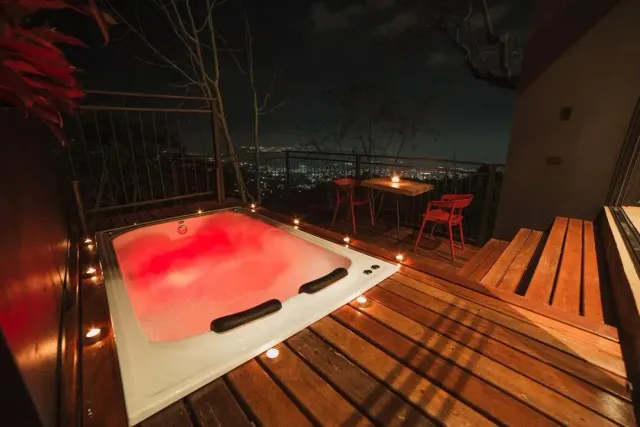 Jacuzzi iluminado con velas y vista nocturna de la ciudad en glamping Bucaramanga.