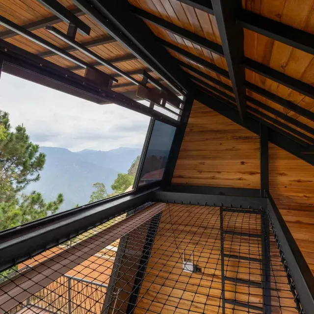 Altillo de cabaña de lujo con estructura en madera y vista a la montaña, diseño abierto ideal para hotel boutique y glamping.