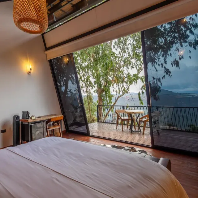 Terraza de cabaña moderna con mesa y ventanales, rodeada de árboles, experiencia de glamping moderno para parejas.