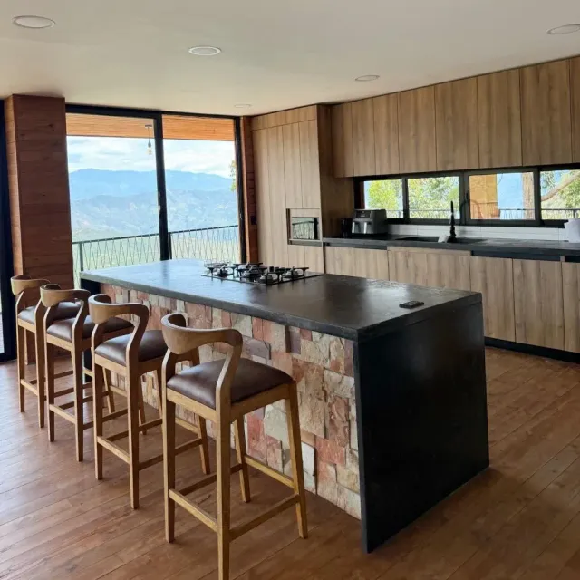 Cocina moderna con isla y sillas de madera en hotel con cocina equipada, vista a la montaña y estilo de cabaña de lujo en glamping.