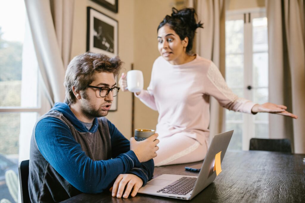 Pareja discutiendo en casa mientras uno de ellos usa la computadora