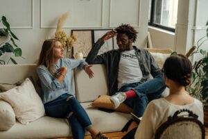 Pareja en sesión de terapia, conversando con una terapeuta en un ambiente acogedor.