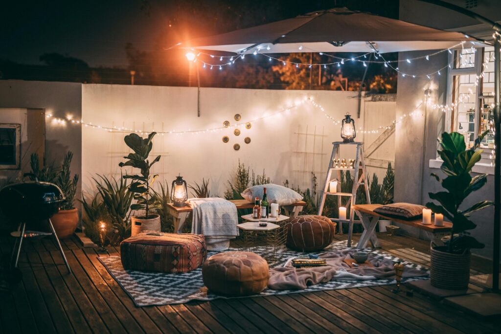 Decoración de patio exterior acogedor con luces, cojines y velas para una noche al aire libre