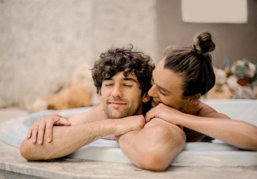 Pareja relajándose en un jacuzzi, disfrutando de un momento íntimo y de descanso.